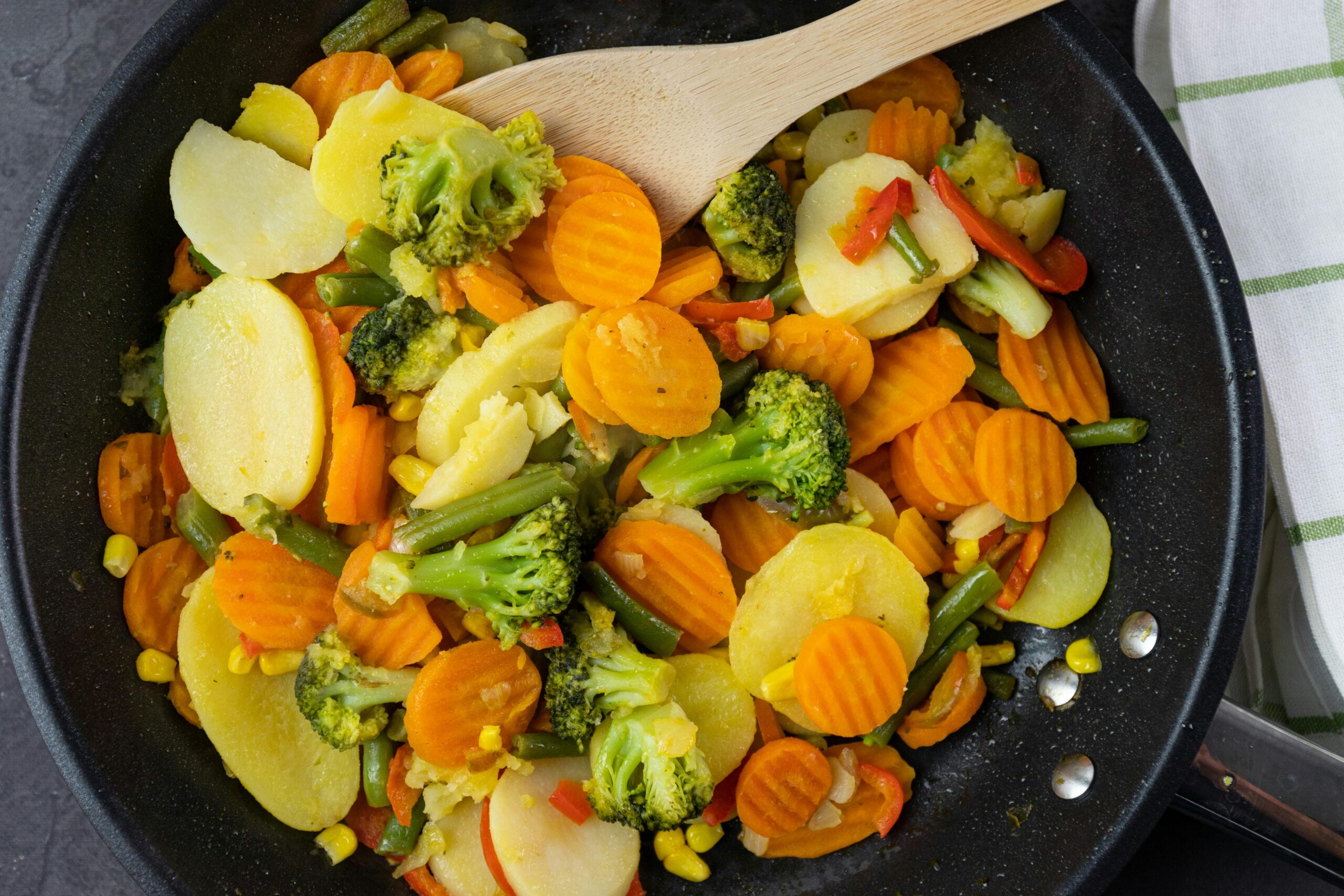 A vibrant mix of stir-fried vegetables including broccoli and carrots in a frying pan.